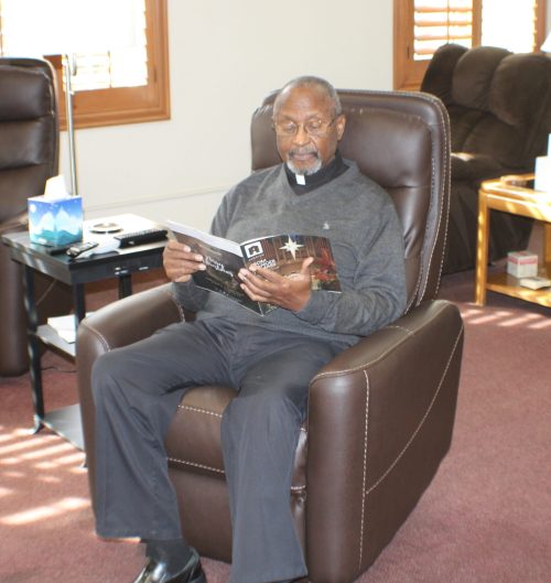 Father Robert Bishop sitting in chair